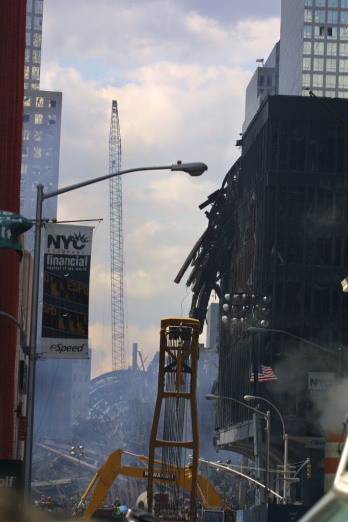 The World Trade Center Site At Ground Zero, Debris And Vehicles Seen Spread Around The Area Already 2 Weeks After The September 11, 2001 Disaster. Cranes Work to Clean Up the Site as Fires are Still Burning Underground And Smoke And Haze Fills The Sky.