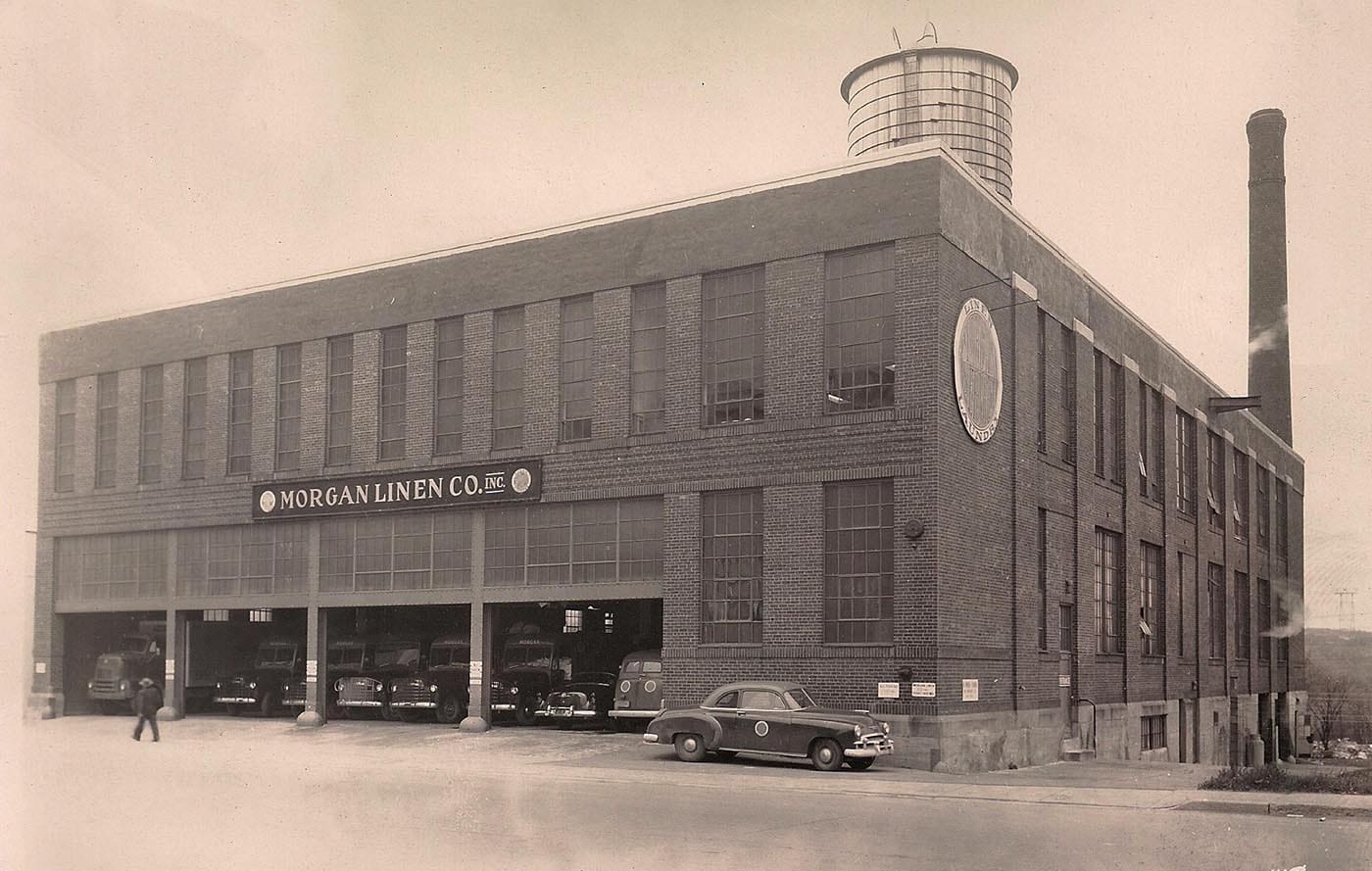 Historic photograph of the Morgan Linen Company factory building with early-20th-century cars parked outside.