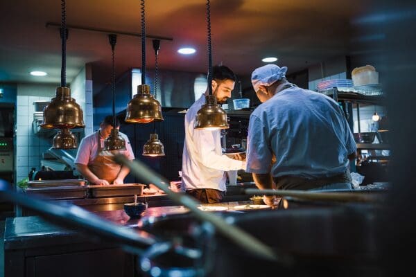 Restaurant staff preparing food in a busy commercial kitchen.