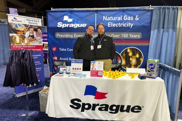 Sprague representatives standing at a trade show booth promoting natural gas and electricity solutions.